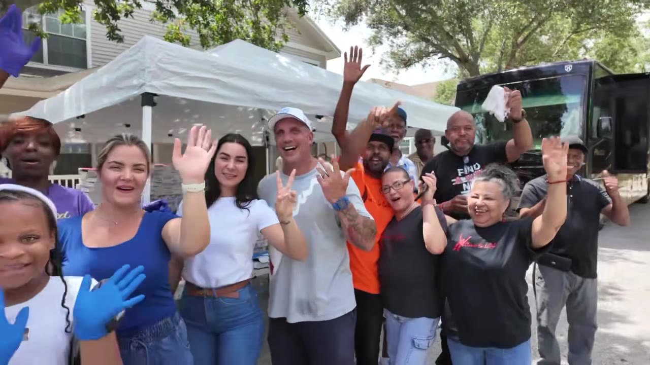 Neighbors gather and wave near a mobile health outreach bus parked in the community