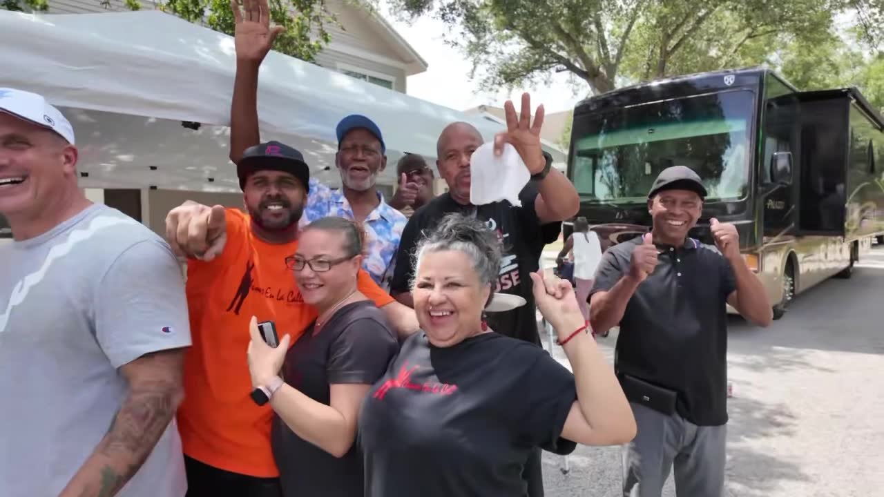 A group of community members celebrating together outside near a tent and outreach vehicle